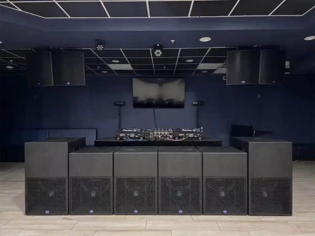 Professional DJ booth setup with Pioneer DJ turntables, large subwoofers