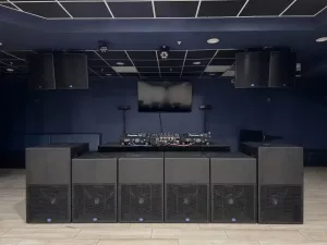 Professional DJ booth setup with Pioneer DJ turntables, large subwoofers