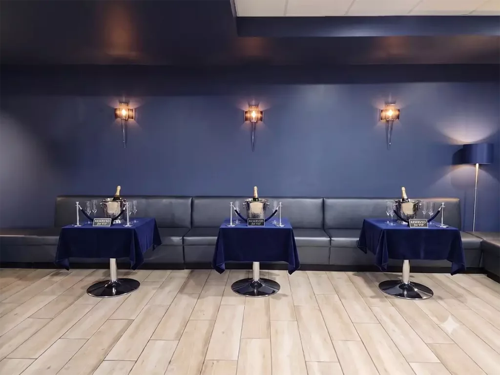 VIP lounge seating at a nightclub featuring long leather banquettes and tables set up with champagne buckets.