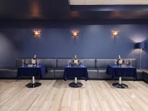 VIP lounge seating at a nightclub featuring long leather banquettes and tables set up with champagne buckets.